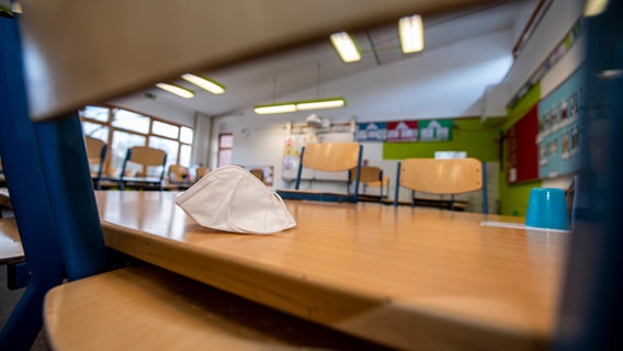 Eine FFP2-Maske liegt auf einem hochgestellten Stuhl in einem Klassenzimmer.
Themenbild: Corona und Schule © picture alliance / Inderlied/Kirchner-Media | Inderlied/Kirchner-Media Foto: Inderlied/Kirchner-Media
