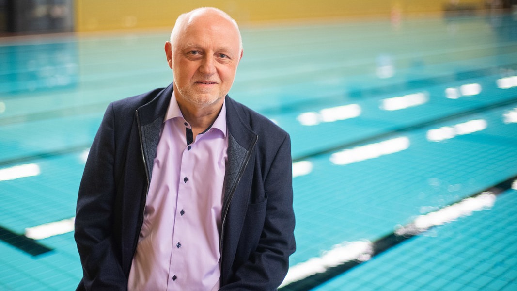 Wolfgang Hein, Vizepräsident des Deutschen Schwimm-Verbandes DSV, sitzt an einem Schwimmbecken.