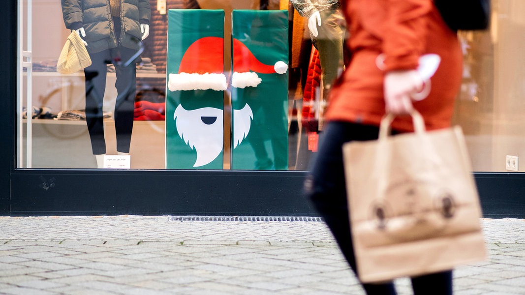 Eine Frau geht in der Innenstadt an einem Geschäft mit Weihnachtsdekoration im Schaufenster vorbei. 