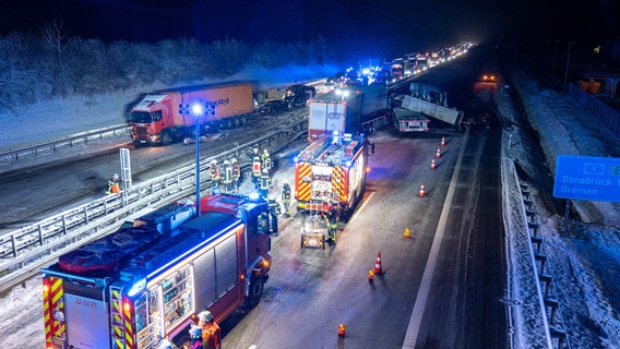 Helfer stehen nach einem Unfall auf der A1 bei Sittensen. Dort war ein mit lebenden Fischen beladener Lastwagen auf winterglatter Fahrbahn verunglückt. © JOTO/dpa Foto: JOTO/dpa