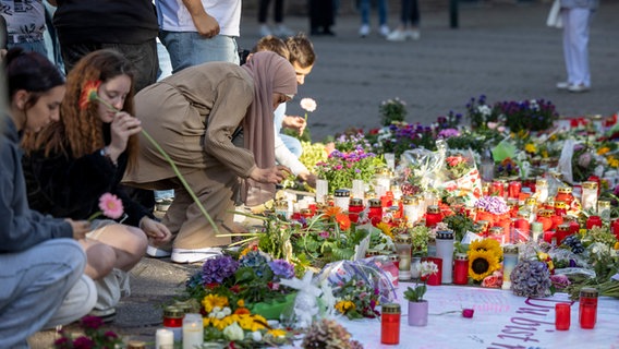 Menschen legen am Tatort in Solingen Blumen und Kerzen nieder, um der Opfer zu gedenken. © picture alliance/dpa Foto: Thomas Banneyer