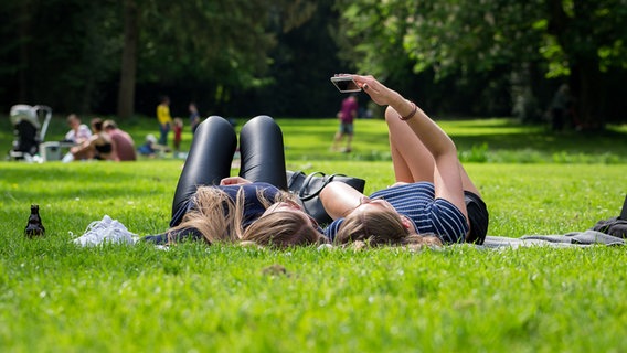 Two women are lying next to each other in a meadow.  © Picture Alliance Photo: Mohssen Assanimoghaddam