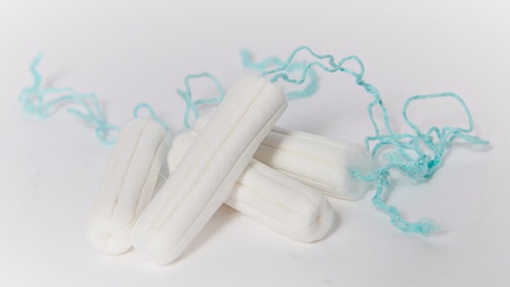 Tampons liegen auf einem weißen Untergrund. © Annette Riedl/dpa Foto: Annette Riedl/dpa