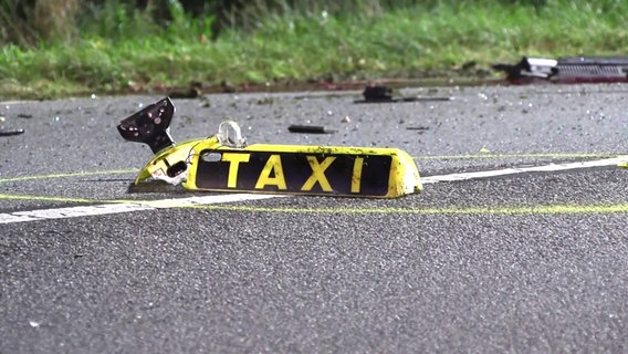 Schild eines Taxis liegt nach einem Unfall mit freilaufenden Pferden in Stade auf dem Boden. Der Taxifahrer starb. © TV-Elbnews 