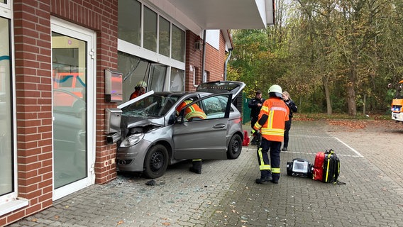 Ein silbernes Auto mit demolierter Frontschürze steckt in einer Zahnarztpraxis fest. © Feuerwehr Braunschweig 