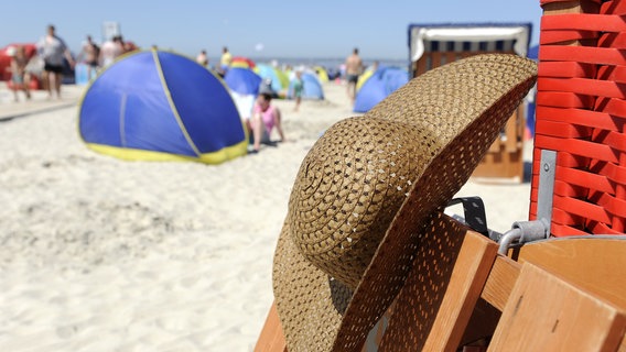 Bei hochsommerlichen Temperaturen hängt am 21. Juli 2013 der Strohhut einer Nordseeurlauberin an einem Strandkorb in Bensersiel. © picture alliance/dpa Foto: Ingo Wagner