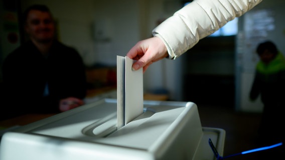 Ein Frau wirft in einem Wahllokal in der Region Hannover ihren Stimmzettel für die Bundestagswahl 2025 in eine Urne. © dpa Foto: Julian Stratenschulte