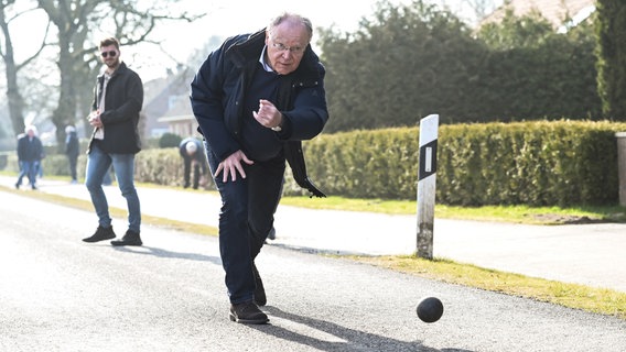 Stephan Weil, SPD-Landesvorsitzender und Ministerpräsident Niedersachsen, wirft die Boßelkugel über die Straße © dpa-Bildfunk Foto: Lars Penning