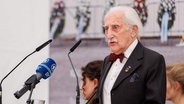 Der Holocaust-Überlebende Leon Weintraub steht beim Gedenkakt zum 78. Jahrestag der Befreiung des KZs Flossenbürg an einem Rednerpult. © picture alliance/dpa | Daniel Karmann Foto: Daniel Karmann