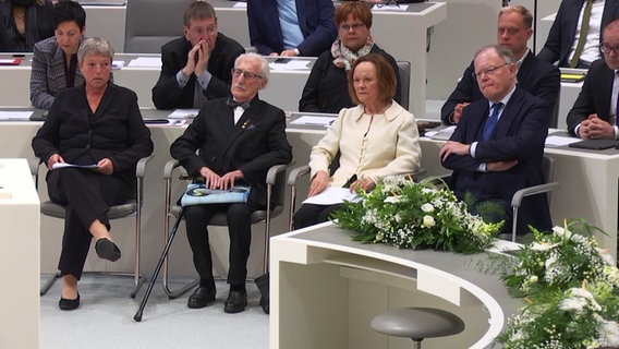 Vor einer Gedenkstunde sitzen Landtagspräsidentin Hanna Naber (von links), der Holocaust-Überlebende Leon Weintraub, dessen Frau Evamaria und Niedersachsens Ministerpräsident Stephan Weil im Landtagsplenum. © NDR 