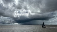 Ein Segelboot auf dem Wasser, im Hintergrund sind dunkle Wolken zu sehen. © NDR Foto: Andreas Depping