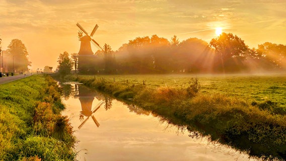 Die Sonne geht hinter einer Mühle in Spetzerfehn auf. © NDR Foto: Marion Holtz