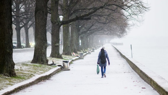 Ein Frau läuft am schneebedeckten Ufer des Maschsees in Hannover entlang. © dpa Foto: Julian Stratenschulte