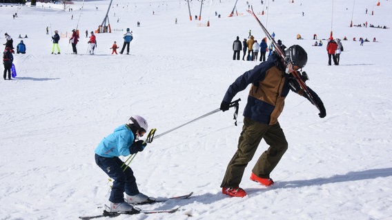 Ein Mann zieht ein Kind auf Skiern hinter sich her. © picture alliance/dpa/dpa-Zentralbild Foto: Waltraud Grubitzsch