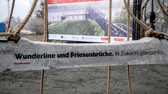 "Wunderlinie und Friesenbrücke" steht auf einer Bahnschwelle, die auf der neuen Bahnstrecke verbaut wird. © dpa-Bildfunk Foto: Sina Schuldt/dpa