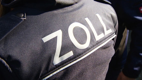 Der Schriftzug "Zoll" steht auf dem Rücken der Jacke eines Zollbeamten. © NDR 