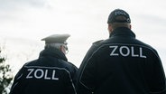 Zwei Männer tragen eine blaue Uniform mit der Aufschrift Zoll auf dem Rücken. © NDR Foto: Julius Matuschik