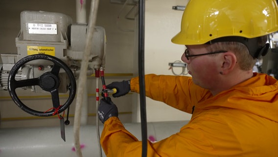 Ein Elektriker bearbeitet eine Leitung mit einer Zange. © NDR Foto: Sven Jachmann