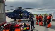 Kieler EInsatzkräfte stehen auf einem Hubschrauberlandeplatz und machen sich bereit zum Abflug. © Feuerwehr Kiel 