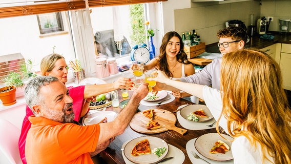 Eine Familie isst am zusammen Pizza und stösst an © picture alliance / dpa-tmn Foto: Zacharie Scheurer