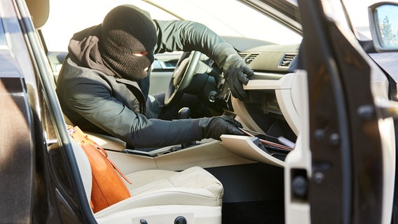 Dieb durchwühlt Handschuhfach im Auto auf der Suche nach Wertsachen. © picture alliance / Zoonar Foto: Robert Kneschke