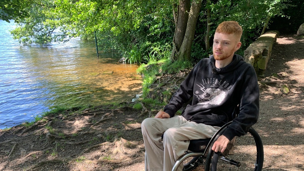 Finn Zielsdorf sitzt in seinem Rollstuhl an einem Ufer.