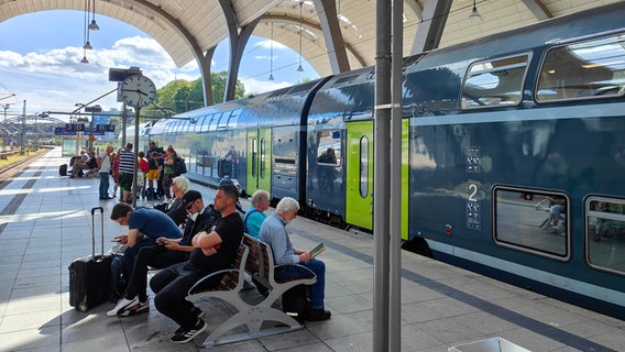 Menschen sitzen auf einem Bahnsteig im Kieler Hauptbahnhof. © NDR Foto: Thomas Viet Dang