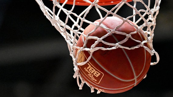 Ein Basketball fällt in einen Basketballkorb. © dpa Foto: Hendrik Schmidt