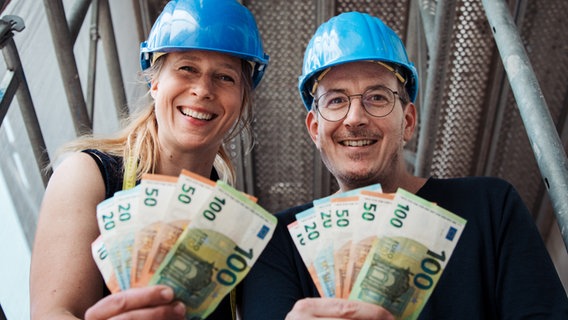 Mandy und Horst sitzen mit Geldscheinen in der Hand auf einem Baugerüst. © NDR Foto: Gino Laib