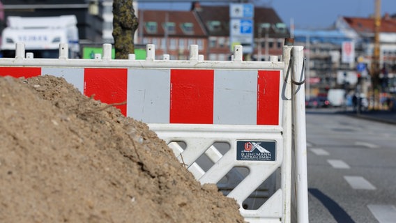 Absperrzaun und ein Haufen Sand stehen am Straßenrand. © NDR Foto: Pavel Stoyan