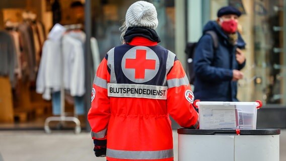 Mitarbeiter vom DRK Blutspendedienst West stehen an einem Infostand in der Fußgängerzone und werben bei den Passanten für Blutspende. © picture alliance / Rupert Oberhäuser Foto: Rupert Oberhäuser