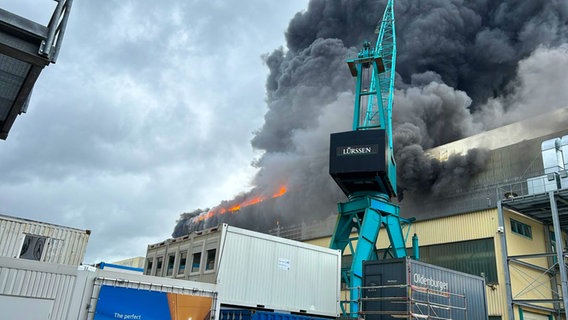 Eine Schiffshalle der Werft Lürssen in Schacht-Audorf bei Rendsburg steht in Flammen. Es steigen große, schwarze Rauchschwaden auf. © Tom Nyfeler Foto: Tom Nyfeler