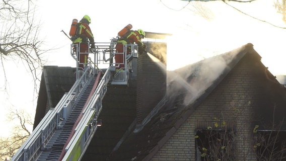 Feuerwehrleute stehen beim Brand eines Hauses in Schellhorn auf einem Löschkran. © Daniel Friedrichsen Foto: Daniel Friedrichsen