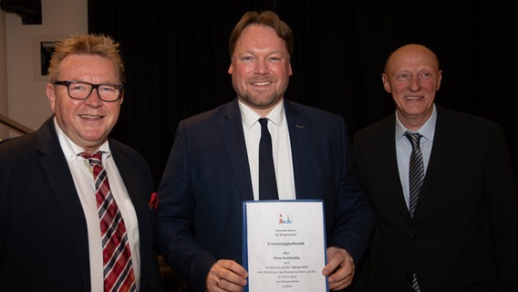 Oliver Kumbartzky (FDP) bei seiner Vereidigung als Büsumer Bürgermeister. Links von ihm der ehemalige Bürgermeister Hans-Jürgen Lütje (Freie Wählergemeinschaft Büsum), rechts von ihm der Bürgervorsteher Gerd Gehrts (CDU). © Gemeinde Büsum 