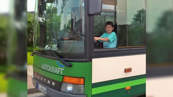 Ein kleiner Junge sitzt hinter dem Lenkrad von einem Bus. © Privat, Lino Fenneberg 