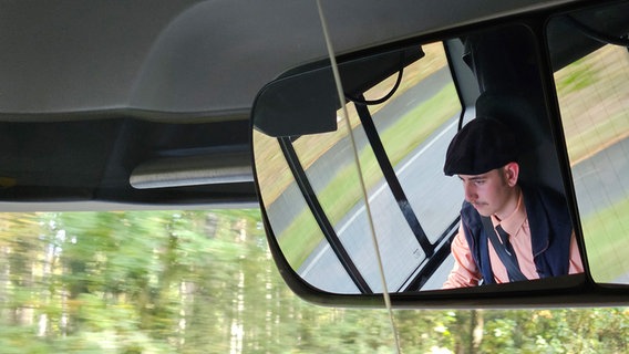 Ein junger Mann sitzt hinter dem Lenkrad von einem Bus. © NDR Foto: Johannes Tran