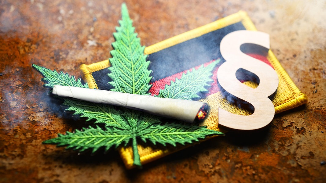 Eine Fotomontage mit Cannabisblatt-Symbol, Joint und Paragrafenzeichen auf Deutschlandfahne,