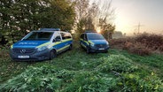 Zwei Fahrzeuge der Polizei stehen vor einem größeren Menge Cannabispflanzen © Polizeidirektion Neumünster Foto: Polizeidirektion Neumünster