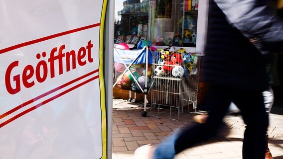 Ein Schild mit der Aufschrift "Geöffnet" steht vor einem Sportgeschäft. © picture alliance/dpa | Frank Molter Foto: picture alliance/dpa | Frank Molter