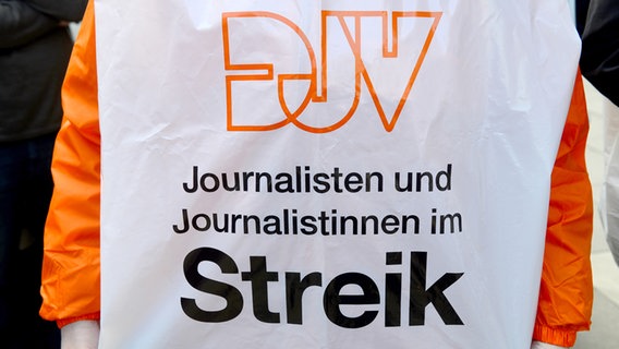 Ein Redakteur trägt während eines Warnstreiks eine Jacke des Deutschen-Journalisten-Verbands. © Picture Alliance Foto: Marcus Brandt