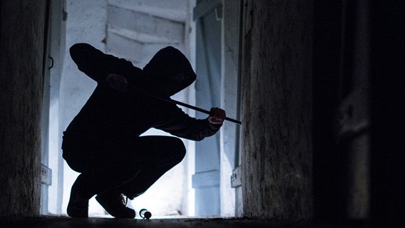 Ein Einbrecher hebelt mit einem Brecheisen eine Tür im Keller eines Wohnhauses auf. © dpa-Bildfunk Foto: Silas Stein