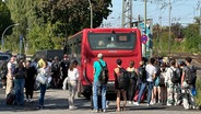 Bahnreisende stehen hinter einem roten Bus in Elmshorn. © NDR Foto: Samir Chawki