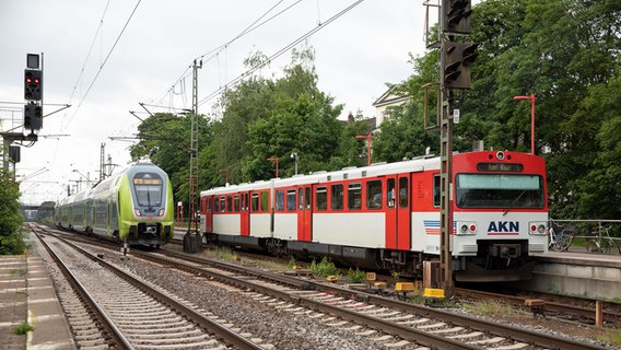 Ein Regionalzug Nah.sh der Deutschen Bahn fährt an einem Triebwagen der AKN Eisenbahn GmbH im Bahnhof Elmshorn vorbei. © picture alliance/dpa Foto: Christian Charisius