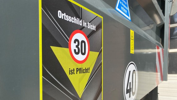 Auf einem großen Trecker-Anhänger ist ein Aufkleber mit der Ausfschrift: "Ortschild in Sicht - 30 ist Pflicht!" zu sehen. © NDR Foto: Joscha Krone