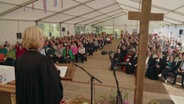 Der Blick von einem Altar in einem Zelt in dem eine Andacht zu einem Erntedankfest gehalten wird © NDR Foto: NDR Screenshot