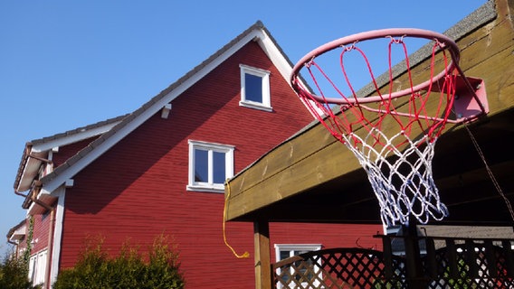 Ein Basketballkorb im Vordergrund eines Einfamilienhauses. © NDR Foto: Hauke Bülow
