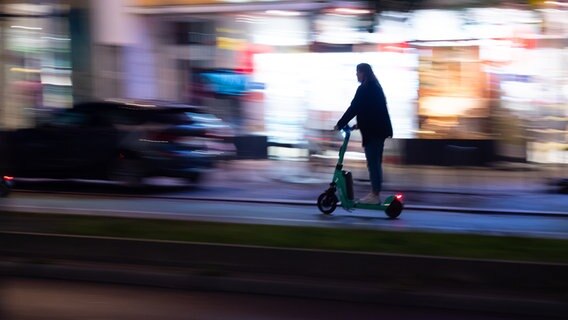 Eine Person fährt auf einem E-Scooter nach Einbruch der Dunkelheit auf einer Hauptstrasse. © picture alliance/dpa Foto: Wolfram Steinberg