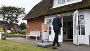 Kampen: Ein Sylter geht am Sonntagmorgen in das Wahllokal im reetgedeckten Kaamp-Hüs in Kampen (Sylt). © dpa Foto: Lea Sarah Albert