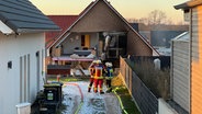 Feuerwehrleute stehen vor einem durch eine Explosion beschädigten Haus © News 5 Foto: René Schröder