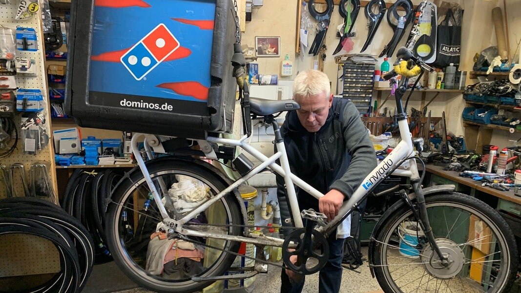Ein Mann repariert ein von der Decke einer Werkstatt hängendes Fahrrad